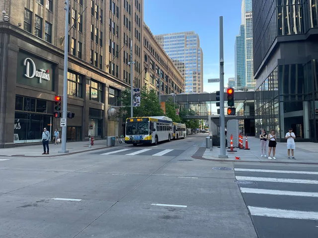 Nicollet Mall looking north across 8th Street in 2024. Metro Transit buses are visible going southbound. Dayton's Building is on the left, IDS Center on the right. NACTO and FHWA guidance in downtown Minneapolis: a Nicollet Mall walk and the skyway