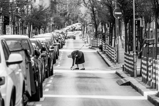 urban, black and white, elderly woman, road, puddle, rainy weather, traffic sign, crosswalk, weather, parking, elderly people, busy street, cityscape, car, city center, walking, so