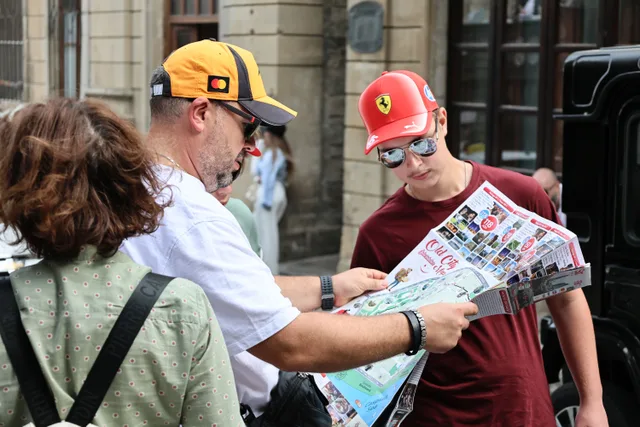 Group of tourists examining a city map, discussing travel plans on a bustling street. Placing your base near tour meeting points, not near the sights